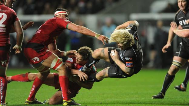 Richard Hibbard of Ospreys is tackled by Aled Thomas of Scarlets in the Boxing Day west Wales Pro12 derby at the Liberty Stadium