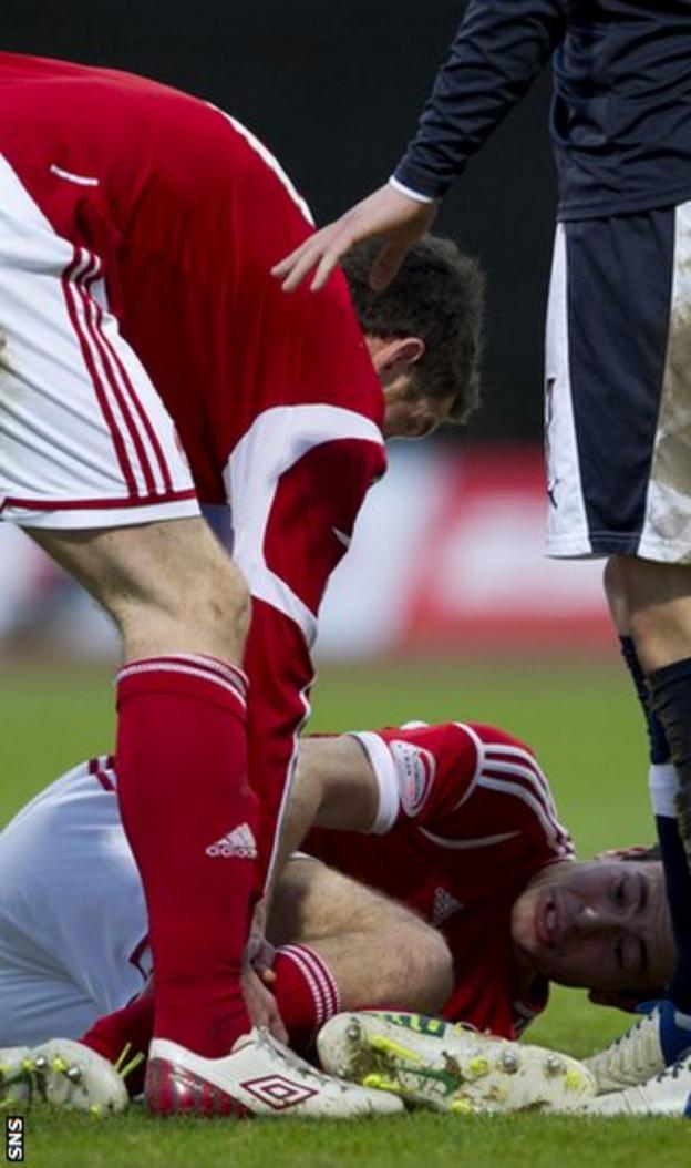 Aberdeen defender Andrew Considine lies injured at Dens Park