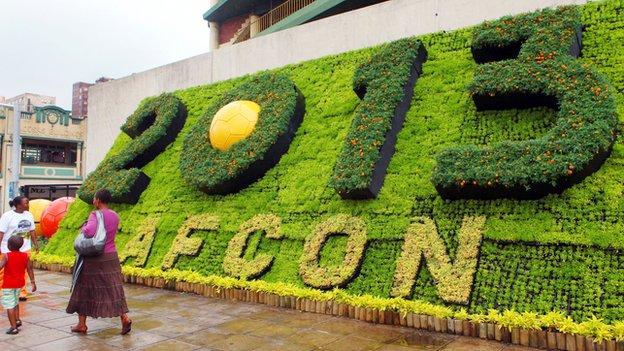 Members of the public walk past a sign promoting the 2013 Africa Cup of Nations in Durban, one of the five South African cities hosting matches during the tournament.