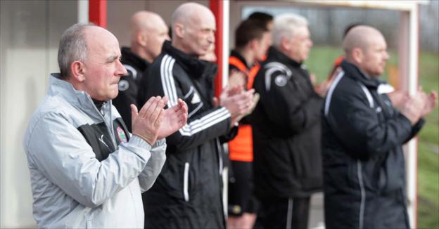 Cliftonville and Lisburn Distillery coaching staff take part in a minute's applause in memory of the late Malcolm Brodie