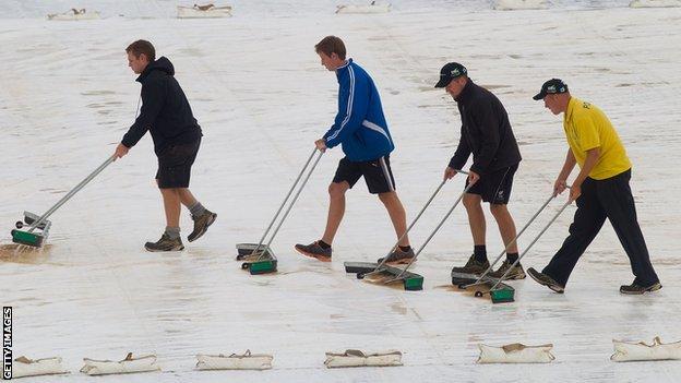 Groundstaff mop water off the Wellington covers