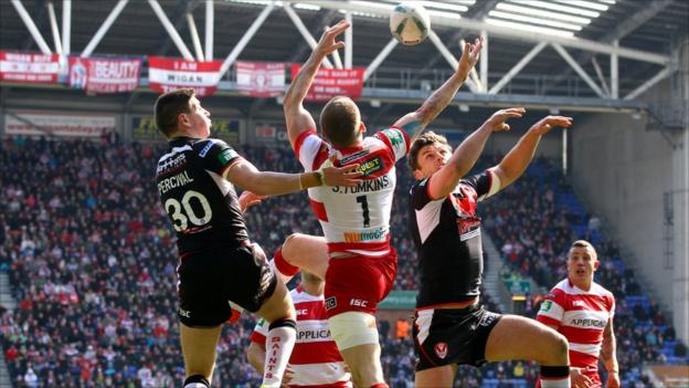 Sam Tomkins of Wigan jumps with St Helens' Mark Percival and Jon Wilkin