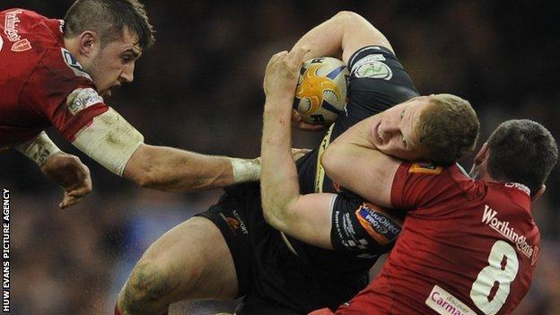Patrick Leach of Newport Gwent Dragons is tackled by Rob McCusker of Scarlets