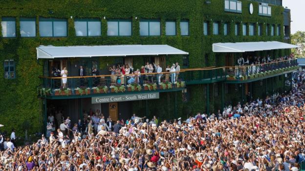 Andy Murray stands on the balcony to show the crowds the trophy