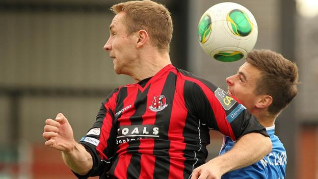 Crusaders striker Timmy Adamson competes for a high ball with Linfield defender Matthew Clarke
