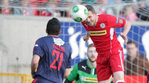 Cliftonville's Marc Smyth heads the ball as Portadown defender Emmett Friars looks on