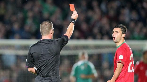 Referee Danny Makkelie shows Helder Postiga a red card for a head-butt on Gareth McAuley late in the first half