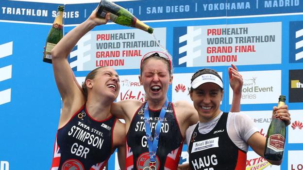 World champion Non Stanford is doused with Champagne by fellow British athlete Jodie Stimpson who finished second in the series. Third-placed Anna Haug joins in the celebrations.