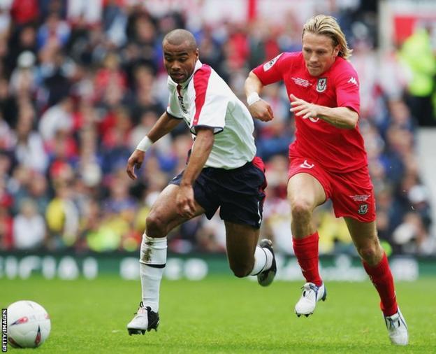Bellamy battles for the ball with England defender Ashley Cole during a World Cup qualifier at Old Trafford in October 2004 - Mark Hughes' penultimate game in charge