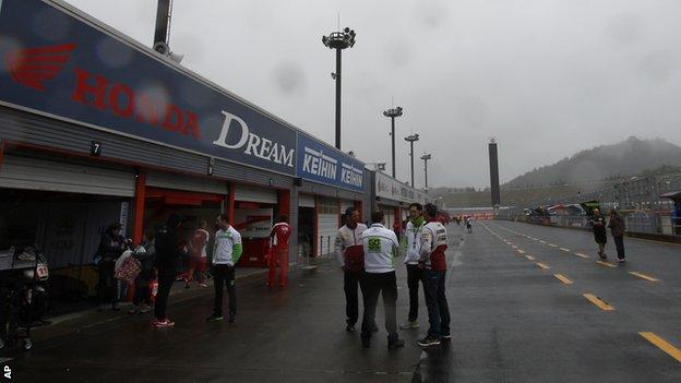 Team members talk in the pit lane after practice was cancelled due to weather during the MotoGP Japanese Grand Prix at the Twin Ring Motegi circuit