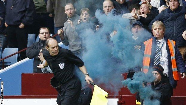 Assistant referee David Bryan is struck by a flare during the Aston Villa v Tottenham Hotspur match