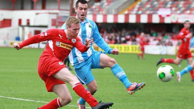 Chris Curran gets his cross in despite the presence of Warrenpoint's Mark Hughes