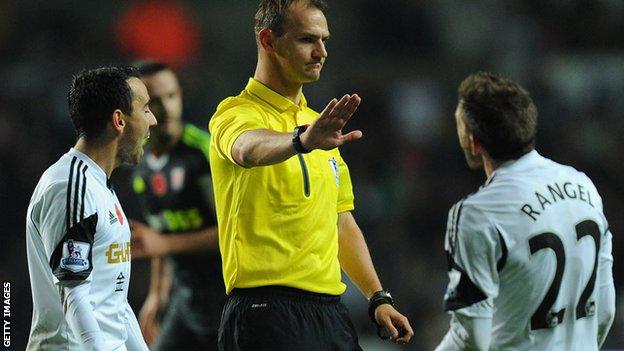 Referee David Madley brushes away the protests of Swansea City players Leon Briton and Angel Rangel