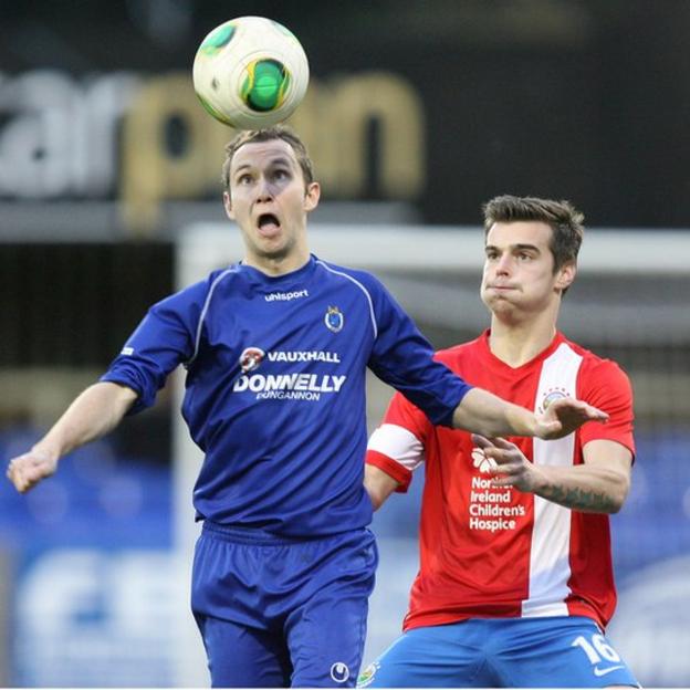 David McCullough of Dungannon Swifts heads the ball as Linfield defender Matthew Clarke moves in to challenge