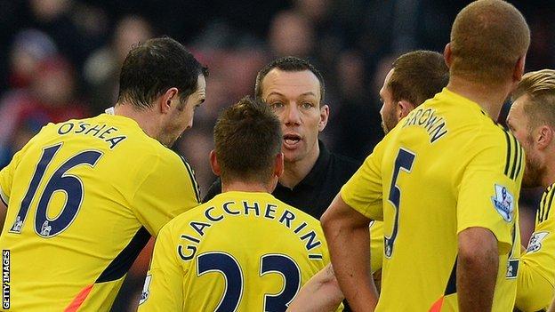 Referee Kevin Friend is surrounded by Sunderland players after sending off Wes Brown