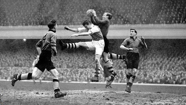 Wolves keeper Bert Williams catches the ball under pressure from Arsenal's Doug Lishman