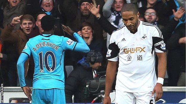 Ashley Williams looks downcast as Emmanuel Adebayor celebrates in front of Tottenham fans