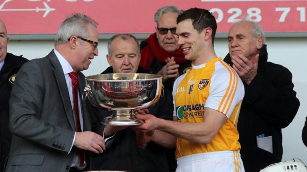 Ulster Council president Martin McAviney presents Antrim hurling captain Neil McManus with the Liam Harvey Cup