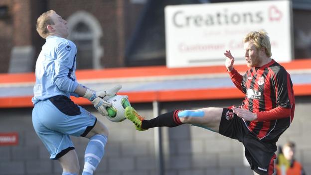 Ballymena goalkeeper Aaron Shanahan collects the ball as former United striker Andy Smith closes in