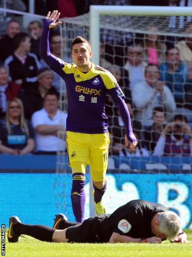 Swansea City's Pablo Hernandez asks for help for referee Chris Foy after the official was hit in the face by the ball