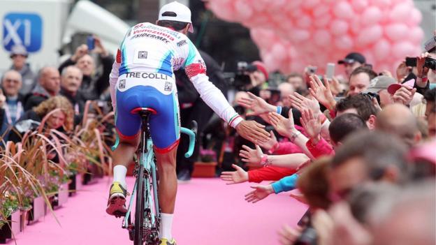 A member of the Italian-based Androni Giocattoli-Venezuela team is greeted by spectators during the Giro d'Italia opening ceremony