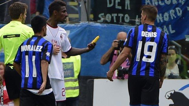 Kevin Constant holding a banana thrown at him during AC Milan's match against Atalanta