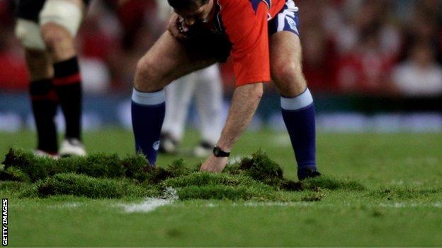 Referee Alain Rolland tries to repair part of Millennium Stadium pitch in 2009