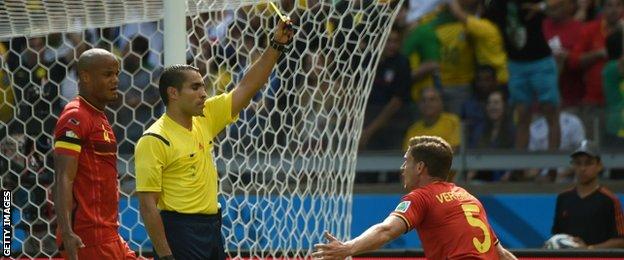 Belgium defender Jan Vertonghen is shown a yellow card after fouling Sofiane Feghouli