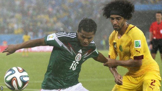 Benoit Assou-Ekotto of Cameroon challenges Mexico's Giovani dos Santos.