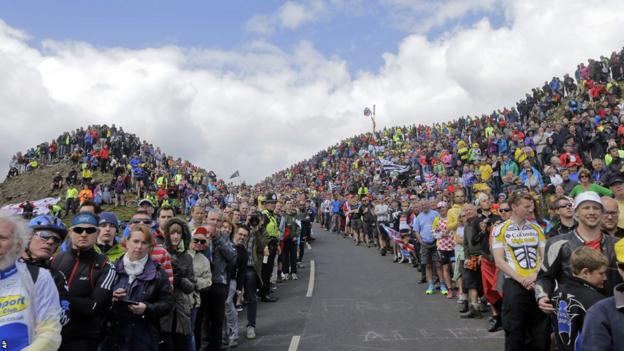 Spectators wait for the cyclists to climb Buttertubs pass during the first stage