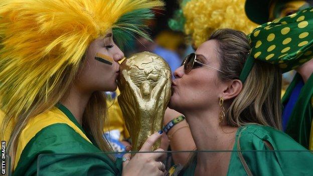 Two Brazil fans kiss a replica World Cup trophy