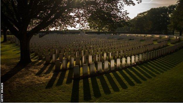 The setting sun creates long shadows in front of the graves at Sanctuary Wood Military Cemetery in Ypres, Belgium