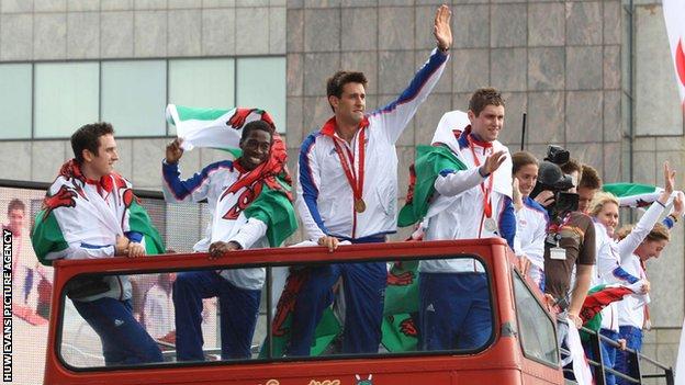 Welsh Olympic athletes wave to the crowds in Cardiff from the top of an open top bus.