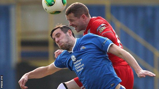 Linfield's Andy Waterworth is btaen to the high ball by Cliftonville defender Marc Smyth
