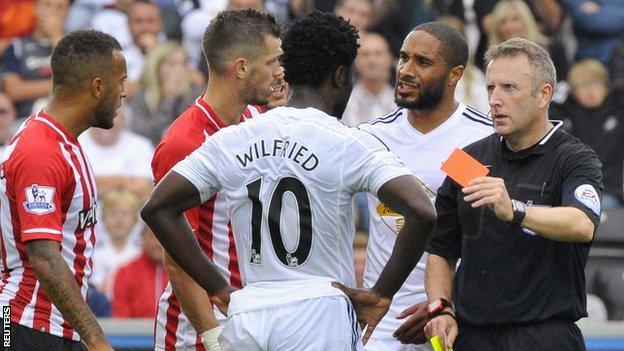 Swansea skipper Ashleigh Williams looks on as Wilfried Bony is shown the red card by referee Jonathan Moss