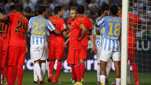 Andres Iniesta looks on as Barcelona and Malaga players argue