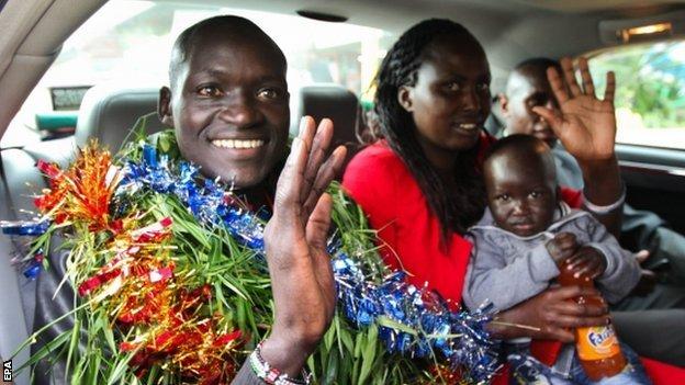 Dennis Kimetto is adorned with garlands as he gets into his car with his family.