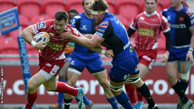Scarlets' Gareth Davies is tackled by Nic Cudd of the Dragons