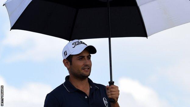 Alexander Levy shelters from rain on the first tee on Sunday