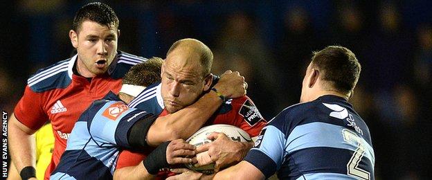 BJ Botha of Munster is tackled by Jarrad Hoeata