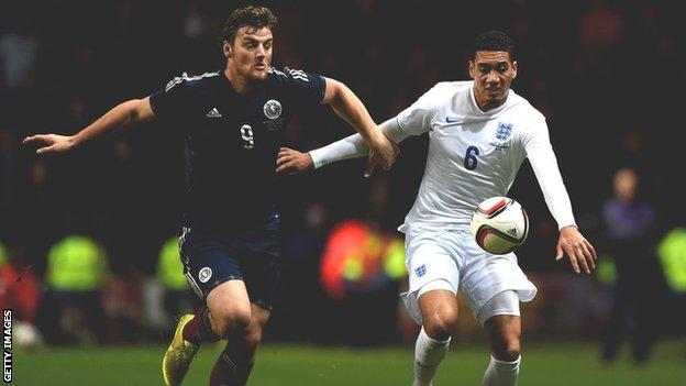 Chris Martin battles for possession with England's Chris Smalling