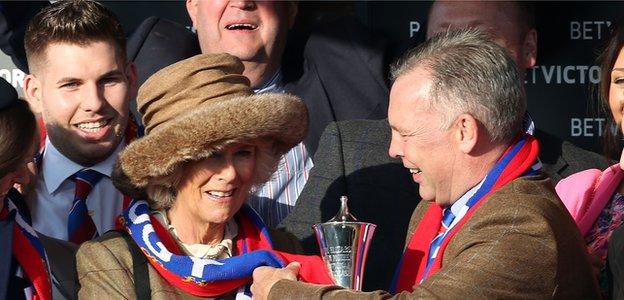 Camilla, Duchess of Cornwall has the winner Sire De Grugy's colours placed around her neck while presenting the trophy to owner Steve Preston