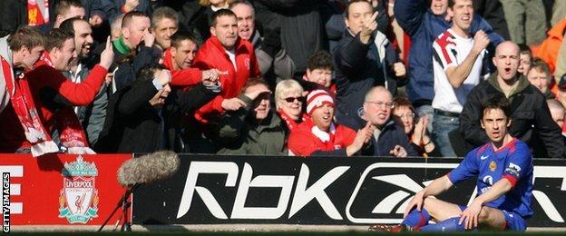 Former Manchester United full-back Gary Neville sits on his backside on the pitch while being taunted by Liverpool fans