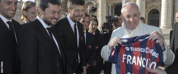 Pope Francis holds a jersey of Argentine soccer team San Lorenzo, given to him as a gift from members of the team, during the Wednesday general audience in St Peter's Square at the Vatican on 18 December, 2013
