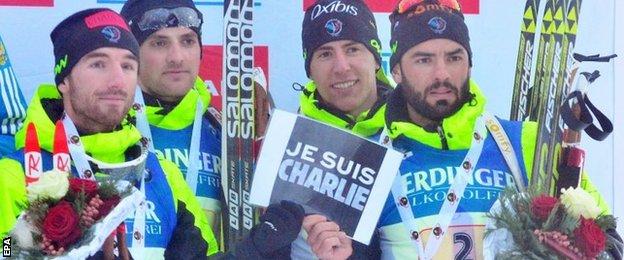 Biathletes Simon Fourcade, Jean Guillaume Beatrix, Simon Desthieux and Quentin Fillon Maillet of France hold up a sign during the award ceremony following the Biathlon World Cup 4 x 7.5 km men's relay competition in Germany