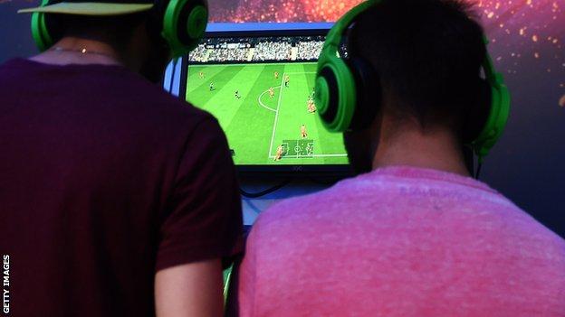 Two males playing football computer game