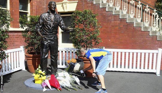 Richie Benaud tributes - a man lays flowers by a statue of Benaud