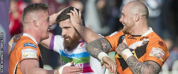 Adam Milner and Nathan Massey celebrate either side of Tyrone McCarthy