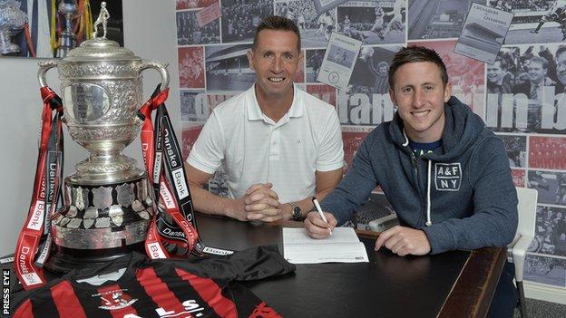 Crusaders boss Stephen Baxter watches Michael Carvill sign his contract