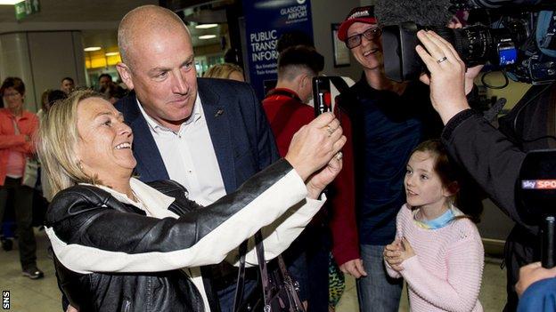 A fan takes a selfie with Mark Warburton as he arrives at Glasgow Airport